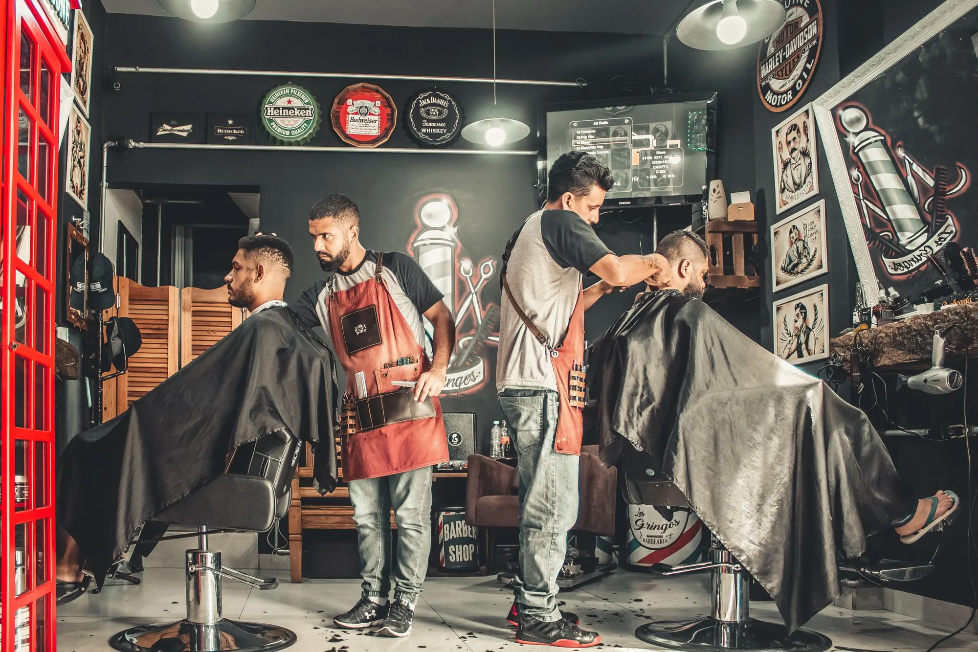 Barberos atendiendo a sus clientes en una barbería
